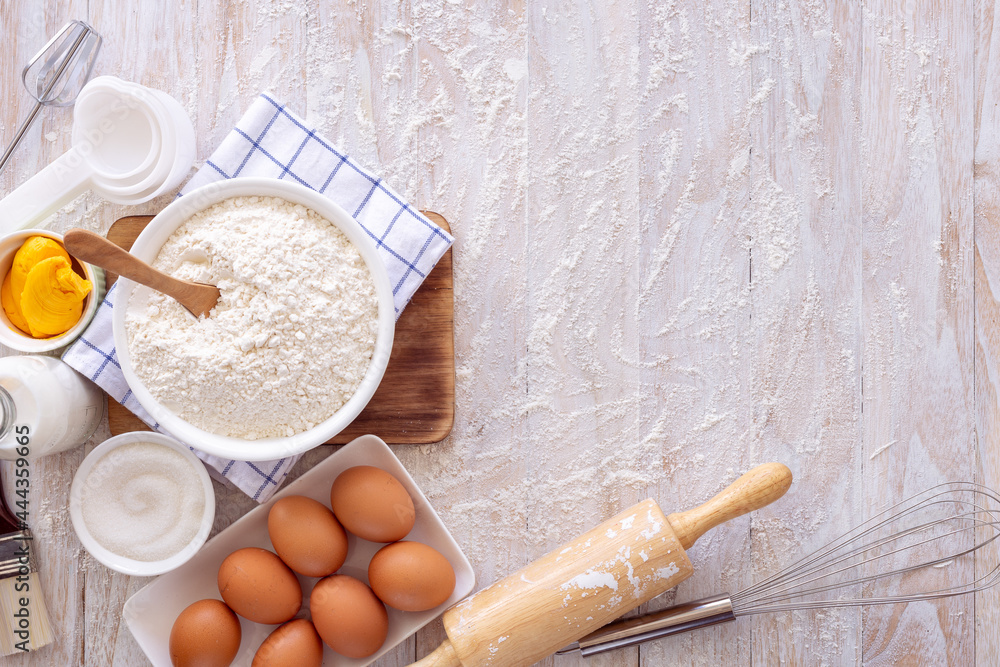 Homemade dough recipe (eggs, flour, milk, sugar) on a wooden table top view. Homemade dough recipe (eggs, flour, milk, sugar) on a wooden table top view.