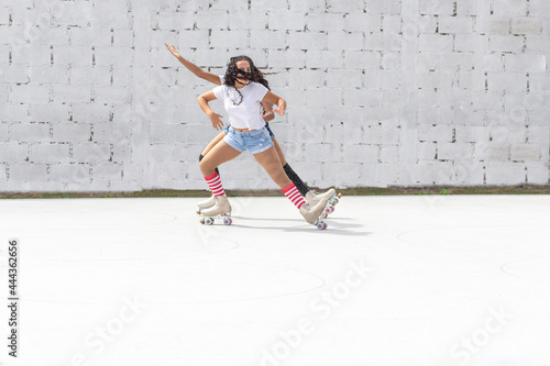 Two teenage Latin girls dressed in shorts and white t-shirt dance fun on four-roller skates