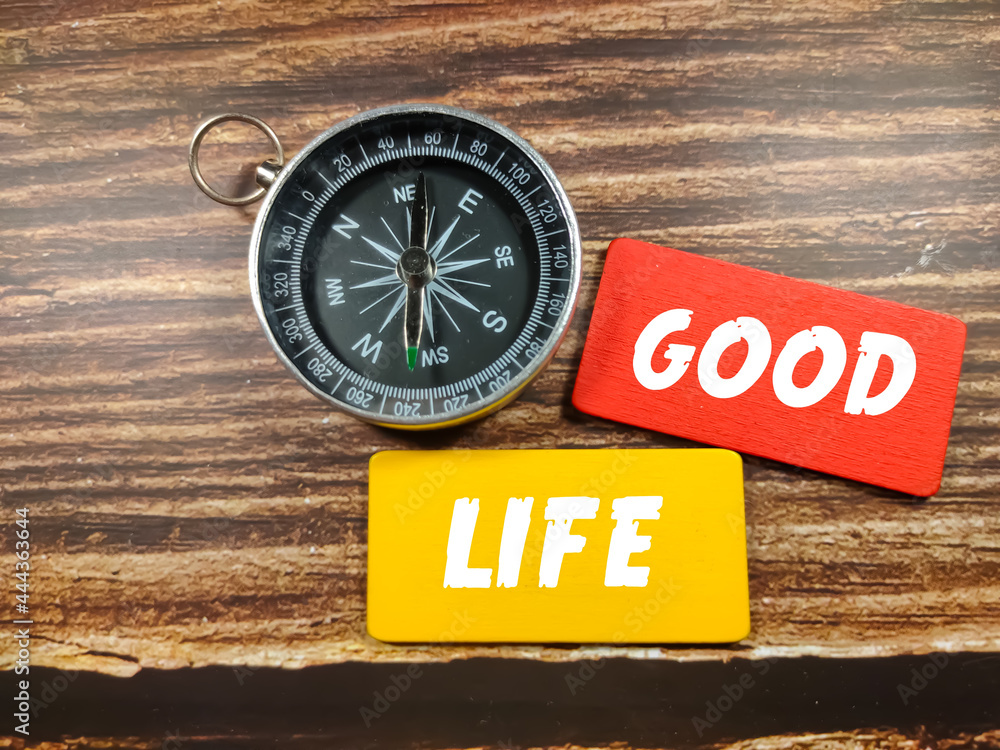 Business concept. Text GOOD LIFE on coloful board with compass on wooden table background. Business concept. Text GOOD LIFE on coloful board with compass on wooden table background.