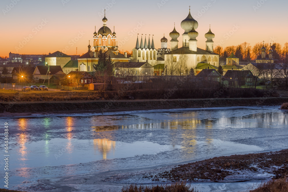 A view of the temples of the Tikhvin Theotokos Assumption Monastery from the side of the Tikhvinka River in the December sunset. Leningrad region, Russia