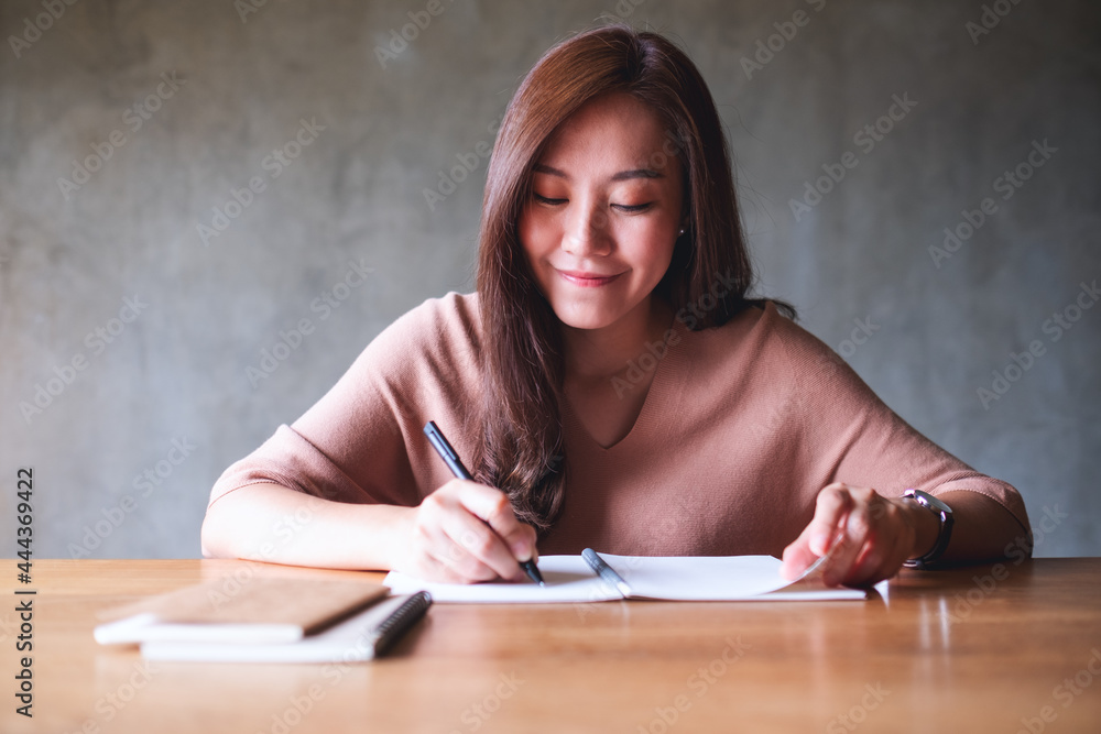 Obraz premium Portrait image of a beautiful young asian woman working and writing on notebook