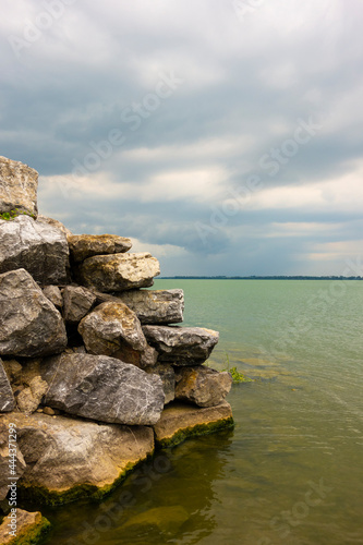 View of the lake with a rocky wall on the right  storm clouds approaching in the background