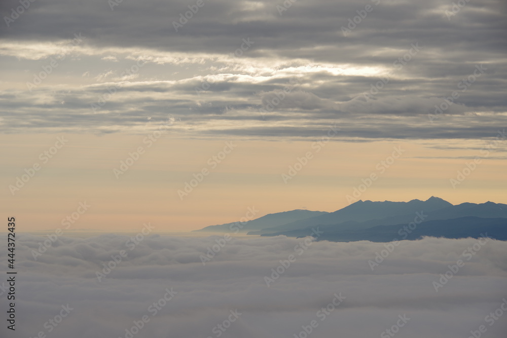 夜明けの空の雲の切れ間に見える山のシルエット。