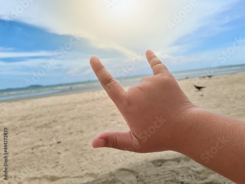 Children raise their hands as a symbol of love at the beach. © squallice