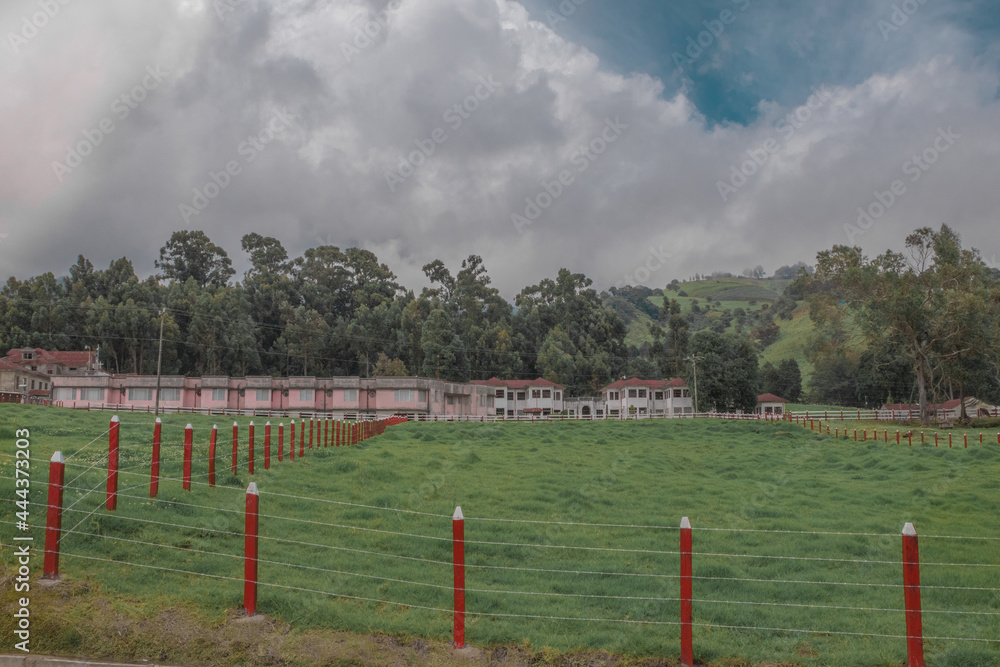 Fototapeta premium horizontal shot green landscape with wooden fences of the gardens and view of the main house Sanatorio Durán on a beautiful and cold afternoon - Cartago - Costa Rica - Central America