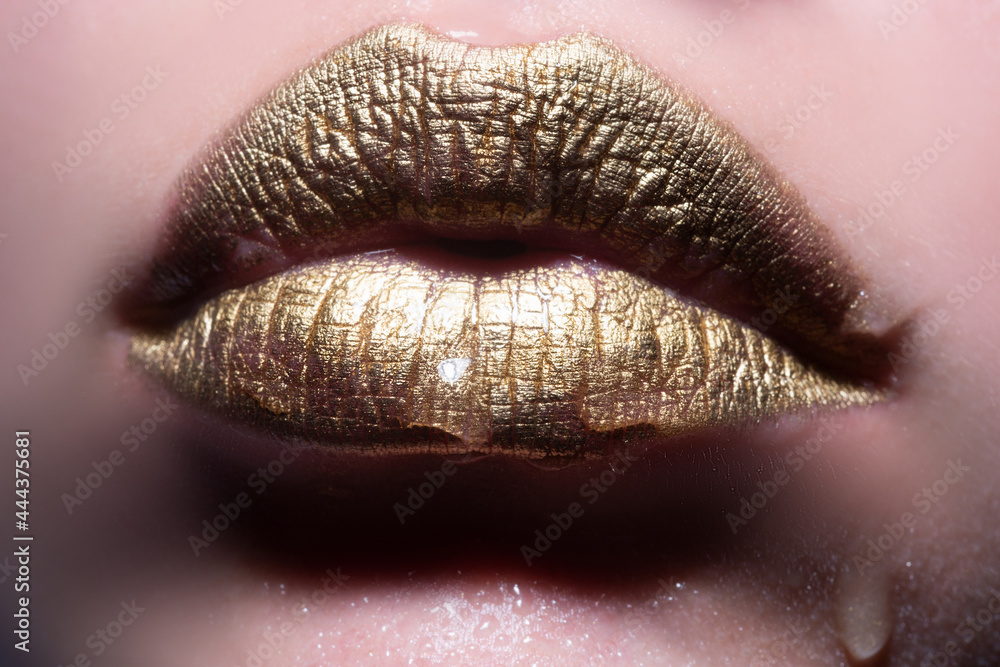 Fototapeta premium Gold lips. Woman wouth close up with golden color lipstick on lip. Glitter glossy lips biting.