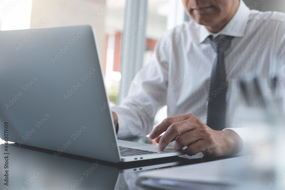 Businessman working on laptop computer with business document on table in modern office Businessman working on laptop computer with business document on table in modern office