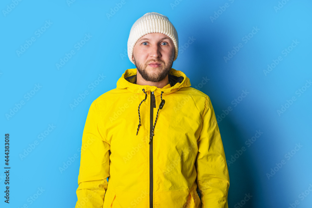 Serious bearded young man in a yellow jacket on a blue background Serious bearded young man in a yellow jacket on a blue background