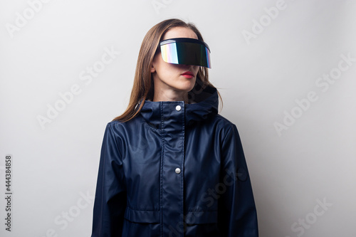Young woman in virtual reality glasses looks to the side on a light background