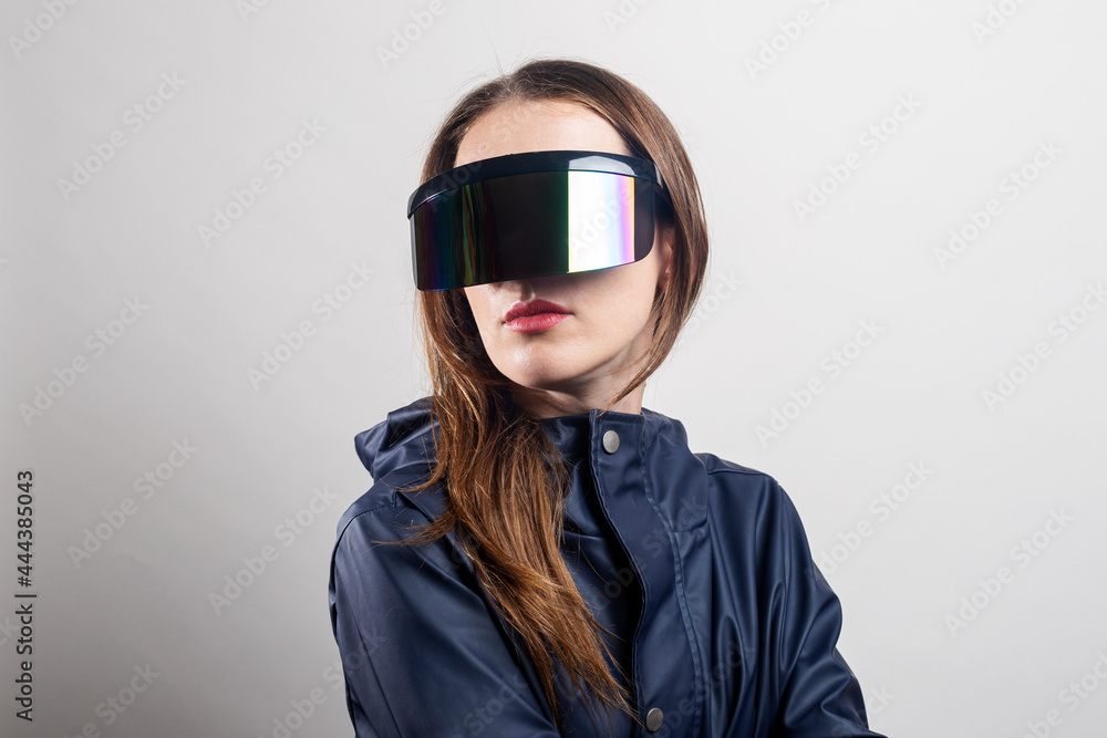 Young woman of the future in virtual reality glasses and in a blue jacket on a light background Young woman of the future in virtual reality glasses and in a blue jacket on a light background
