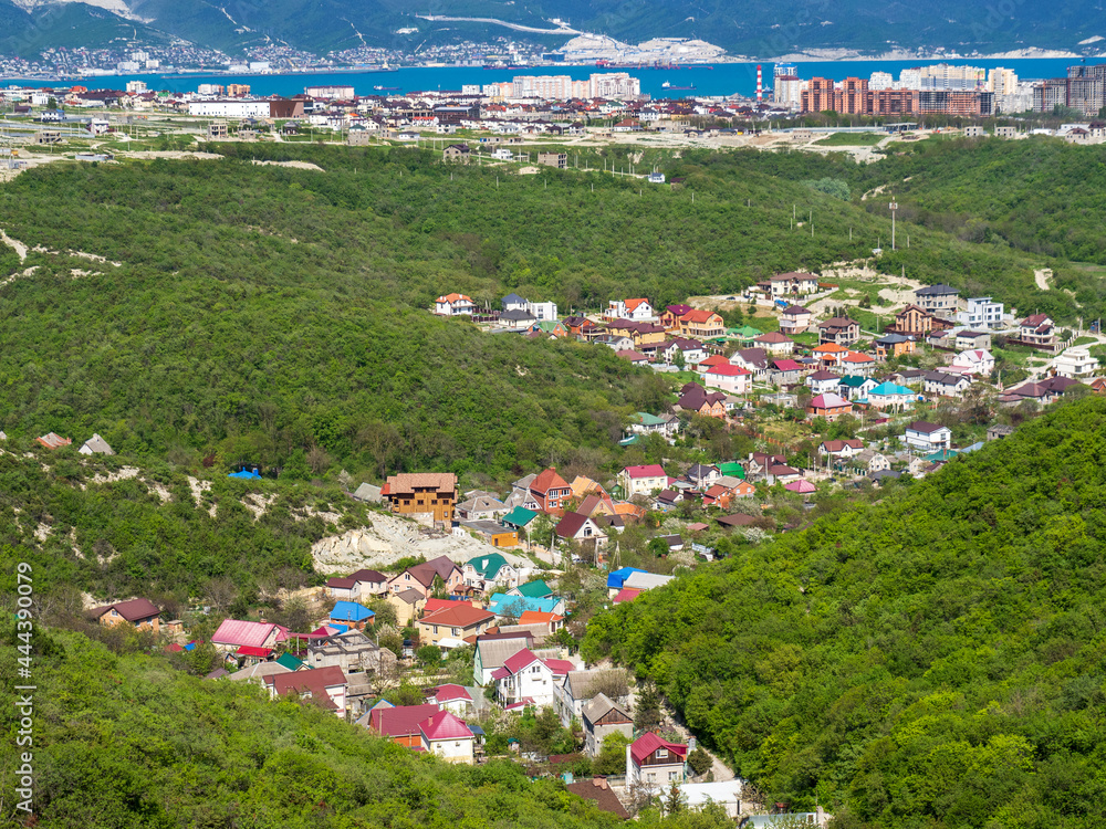 A beautiful panorama on the Black Sea coast. Mountain scene view of the town landscape and village houses between the green hills. The port city of Novorossiysk.