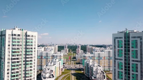 Aerial view of a big city district with sunny streets and high rise residential buildings on blue sky background. Video. Beautiful colorful city area, concept of urbanization. photo