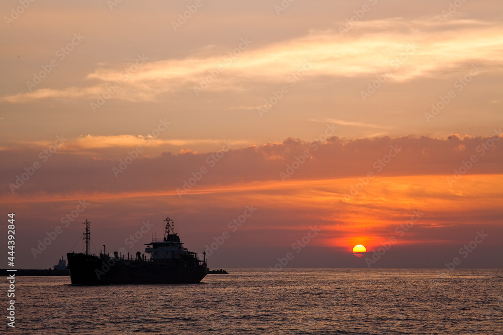 Sunset into the sea with the large ship silhouette in Kaohsiung, Taiwan.