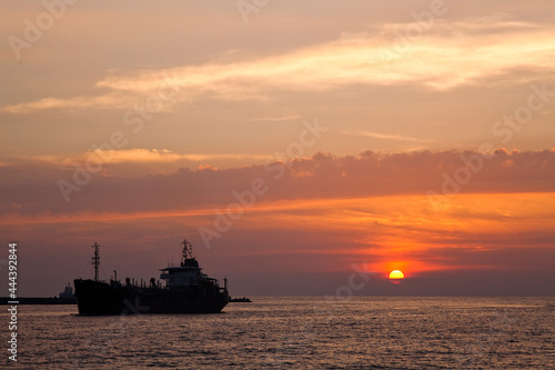Sunset into the sea with the large ship silhouette in Kaohsiung, Taiwan. © BINGJHEN