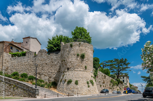 Part of the ancient city walls of the historic center of Castiglione del Lago, Italy, on a sunny day with white clouds