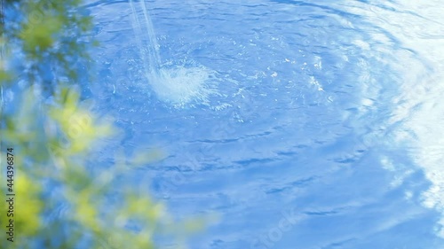 Refreshing Water jet on the water and green leaves unfocused at foreground