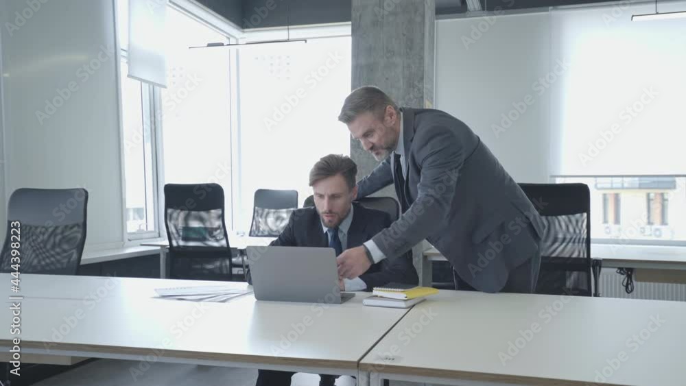 Friendly colleague helping man with business task in office, team atmosphere Friendly colleague helping man with business task in office, team atmosphere