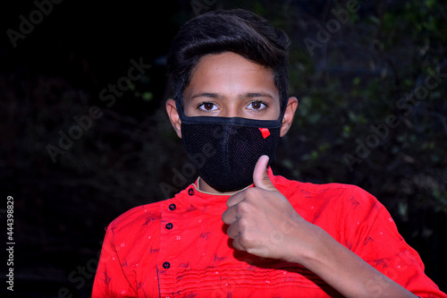 13 years old Asian cute boy wearing protective mask, holding thums up, prevention of Corona virus (Covid -19) and pollution photo