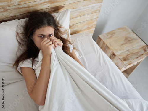 woman pulls the blanket over herself in the morning unwillingness to get up photo