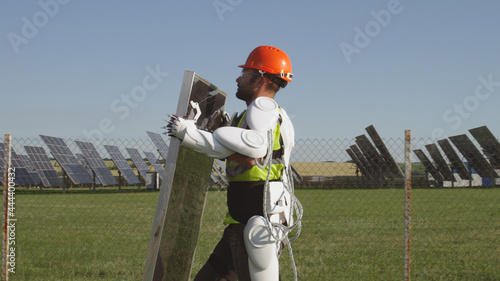Male technician in exoskeleton carrying photovoltaic panel