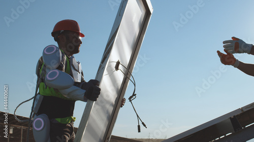 Male technicians assembling solar panel against blue sky