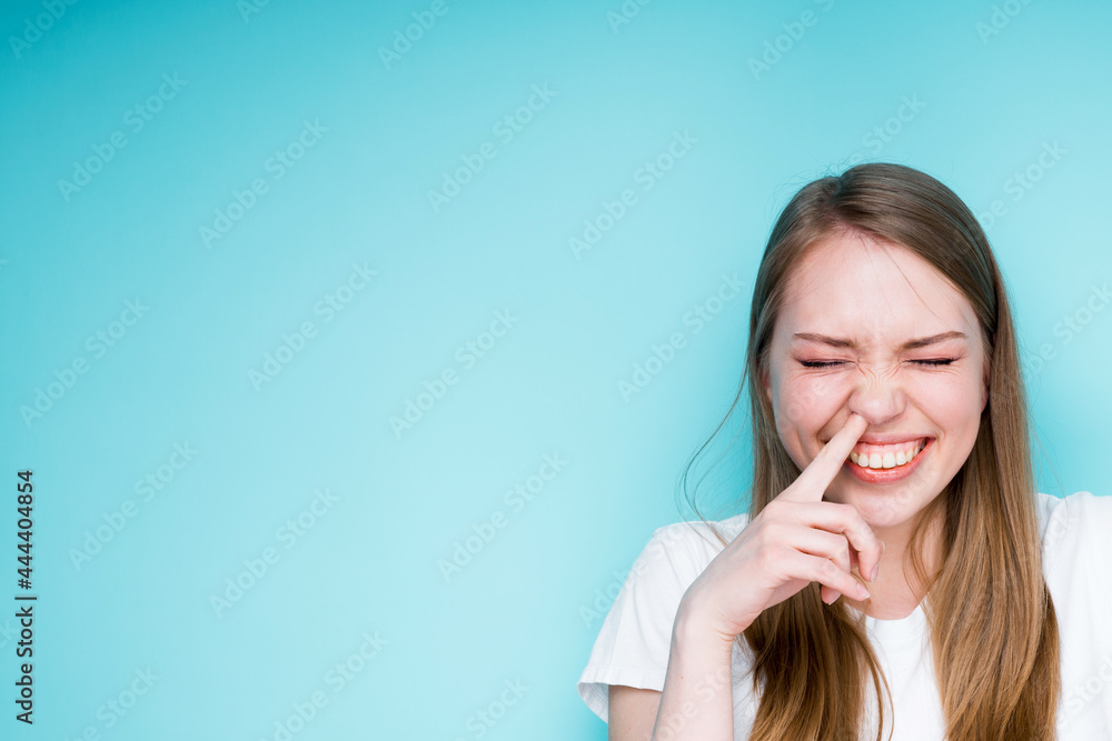 Portrait of a beautiful young girl touching her nose with her finger and closing her eyes laughing Portrait of a beautiful young girl touching her nose with her finger and closing her eyes laughing