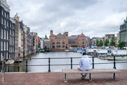 Een man zit op een bankje op het Damrak in Amsterdam photo