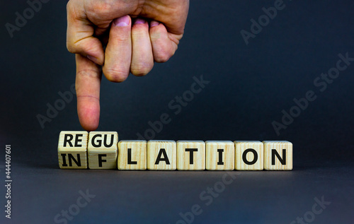 Inflation or regulation symbol. Businessman turns cubes and changes the word inflation to regulation. Beautiful grey table, grey background, copy space. Business, inflation or regulation concept.