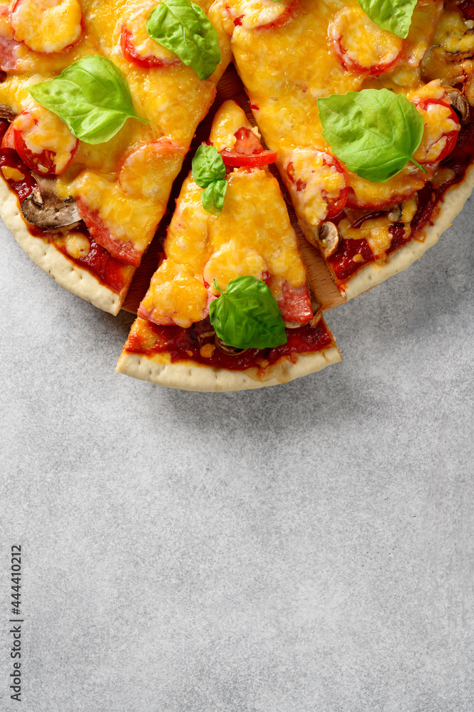 Top view of hot tasty homemade pizza with green basil leaves on the grey concrete background. With copy space for text. Flat lay, close-up Top view of hot tasty homemade pizza with green basil leaves on the grey concrete background. With copy space for text. Flat lay, close-up