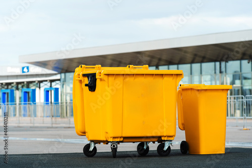 A large and small yellow trash can on a city street. Copy space
