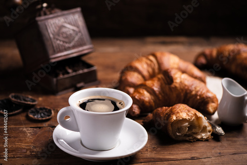 Coffee cup with a croissant on a rustic wooden table