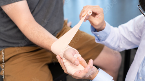Medical concept a male doctor bandaging a male patient   s injured hand caused by sports workout