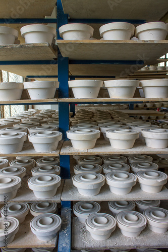 Blanks of white ceramic unfired dishes standing in rows on metal racks at a porcelain factory in the Moscow region in Russia
