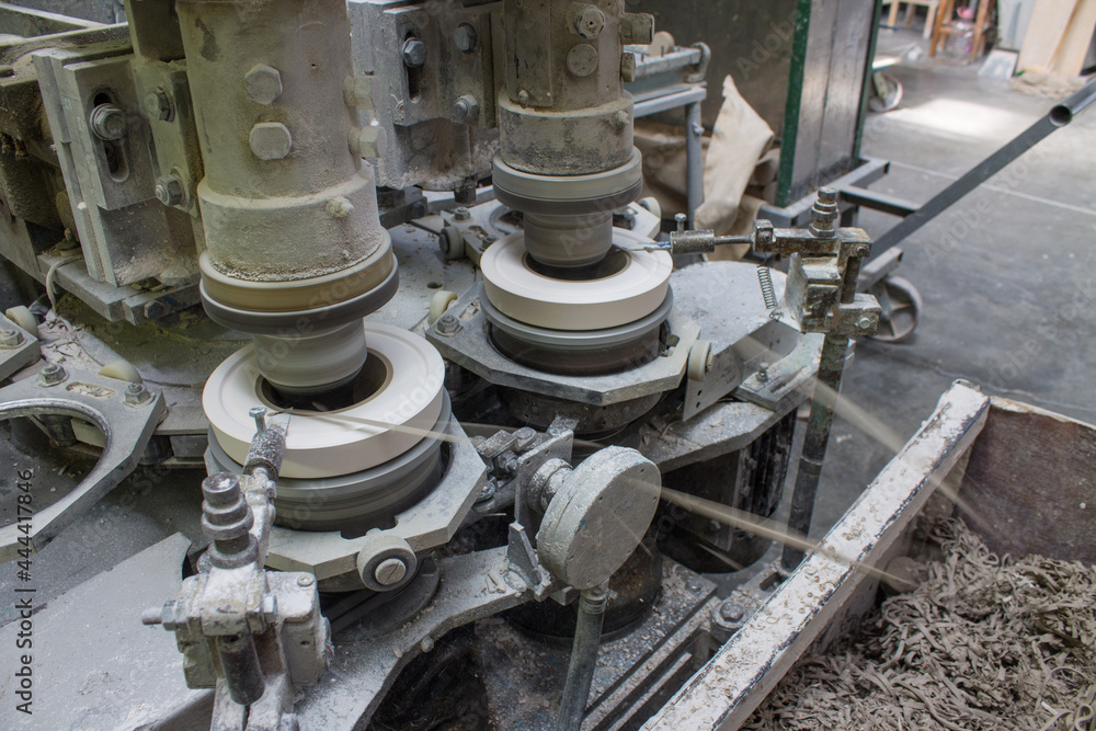 Metal rotating machine for making ceramic tableware from clay tableware close-up at a porcelain factory Metal rotating machine for making ceramic tableware from clay tableware close-up at a porcelain factory
