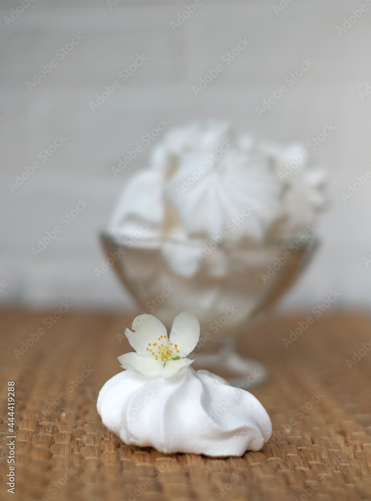 Meringue cake, in a glass vase with a jasmine flower on a wicker background