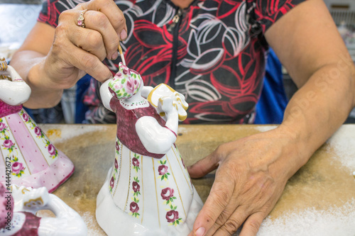 LIKINO-Dulyovo, Moscow Region, Russia-July, 8, 2021: a woman with a hidden face paints a ceramic figurine with a brush at a porcelain factory. Concept-handmade and craft photo