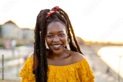 Happy young woman with dreadlocks outdoors
