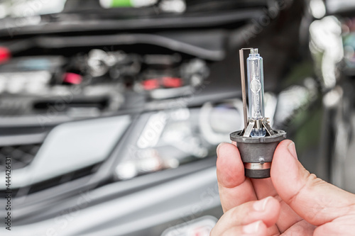 Close up car headlights xenon Lighting Equipment in hand a man with engine room for maintenance concept of car