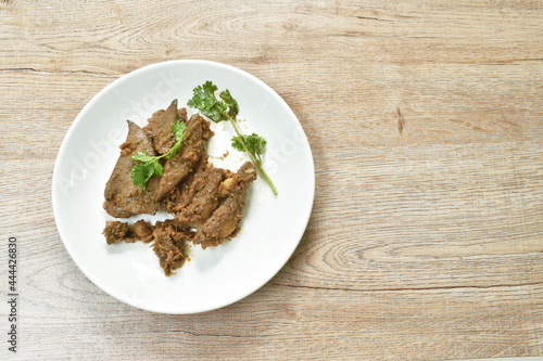 fried slice pork meat and liver with garlic couple pepper topping parsley on plate