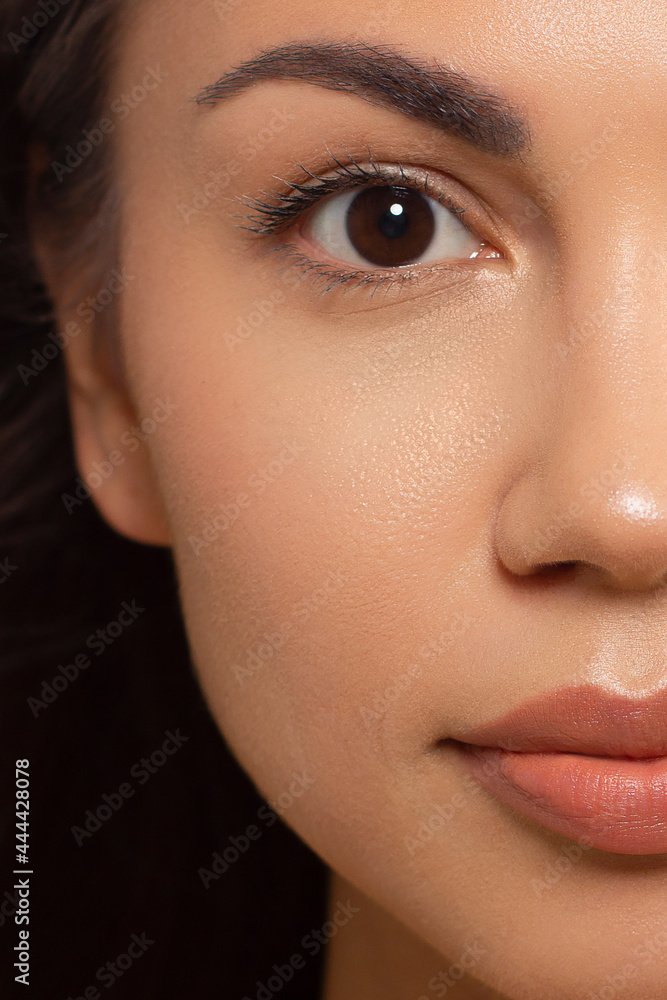 Naklejka premium Closeup of beauty woman with clean shiny skin and natural cosmetics. Beautiful grey eyes and plump lips of a well-groomed girl demonstrate spa procedures, injections in a beauty parlor