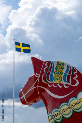 vertical view of a colorful Swedish Dala horse and the Swedish flag under an expressive sky photo