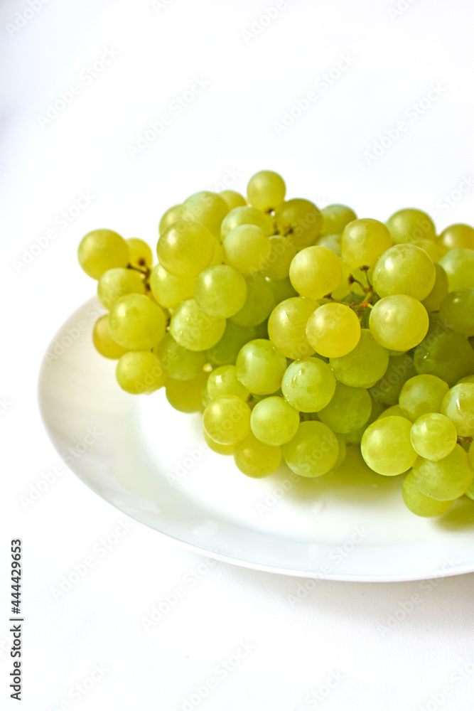 Green juicy delicious grapes on a white plate Green juicy delicious grapes on a white plate