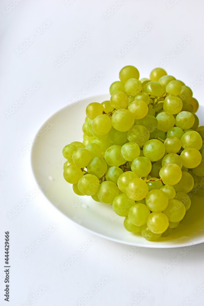Green juicy delicious grapes on a white plate Green juicy delicious grapes on a white plate