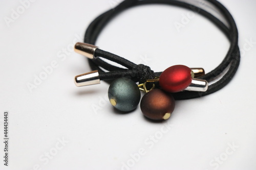 A black colored hair band with the colored stones kept in the white background photo
