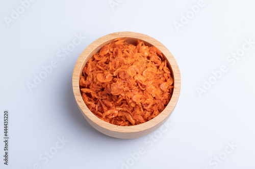 Orange dried shrimp in a wooden cup on a white background.