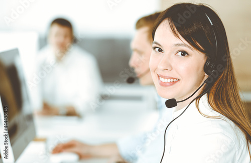 Group of diverse operators at work in call center. Beautiful asian woman sitting in headset at customer service office. Business concept