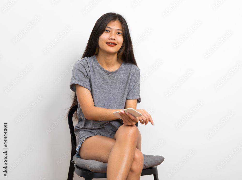 Beautiful young Asian woman smiling sitting relax in the room, using smart phone on white background. Beautiful young Asian woman smiling sitting relax in the room, using smart phone on white background.