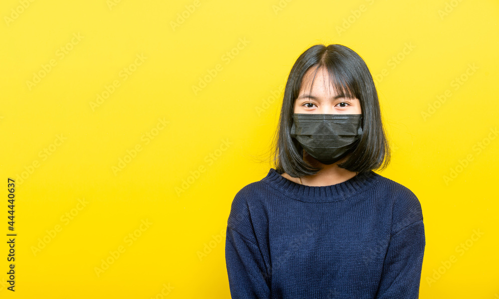 Studio portrait of young girl wearing medical face mask against coronavirus. Background of yellow color. Studio portrait of young girl wearing medical face mask against coronavirus. Background of yellow color.