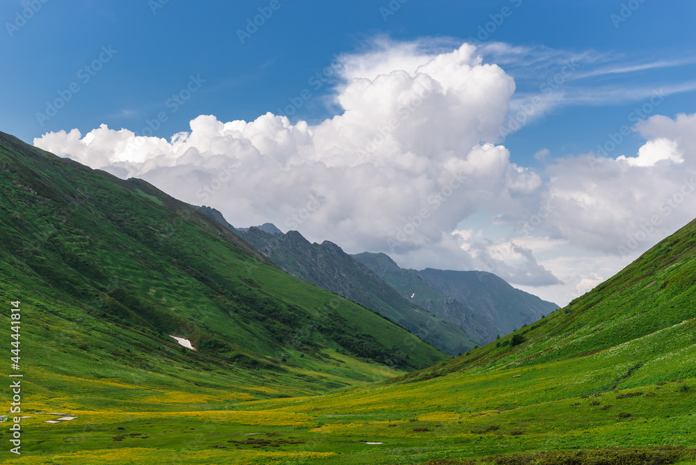 Beautiful green flowering alpine meadows on the Bzerpinsky cornice in Krasnaya Polyana, Sochi. Mountains and sky with clouds