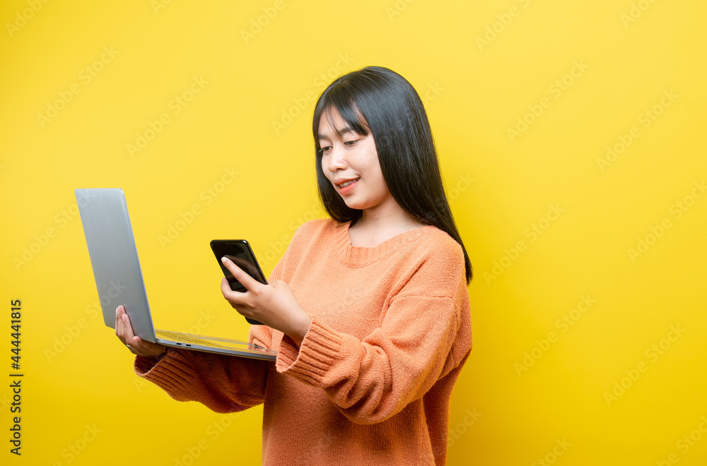 Full length body size turned photo of cheerful positive cute nice attractive blogger browsing through her laptop in search of new information isolated over yellow vibrant color background Full length body size turned photo of cheerful positive cute nice attractive blogger browsing through her laptop in search of new information isolated over yellow vibrant color background